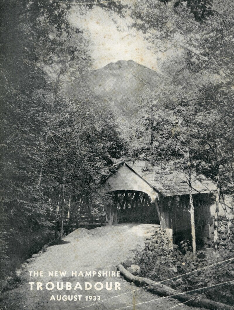 A covered bridge surrounded by trees with a mountain visible in the background, the Flume covered bridge with Mt. Liberty.